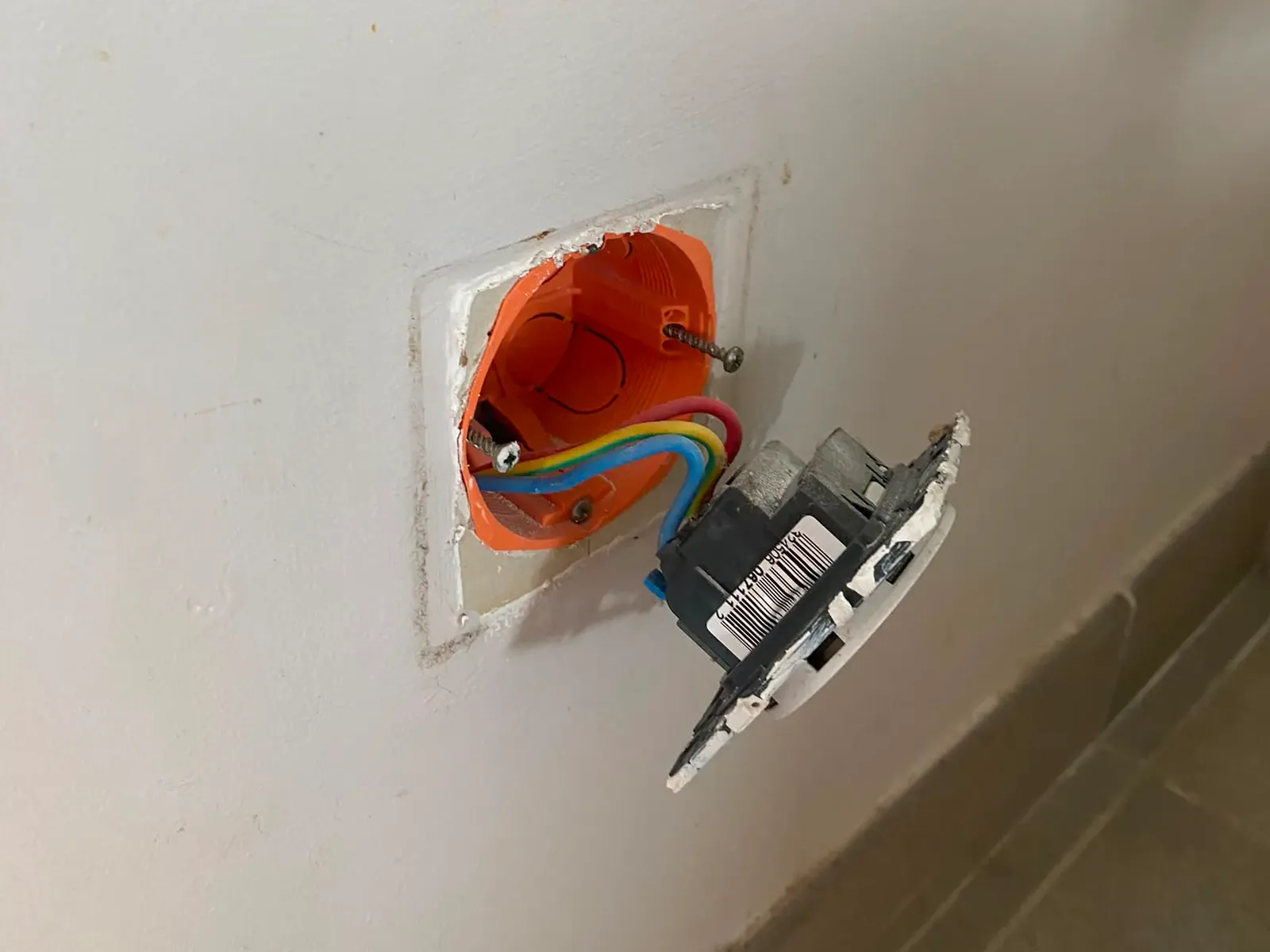 Prise déposée de sa boîte d'encastrement pendant un dépannage réalisé par CC ELEC